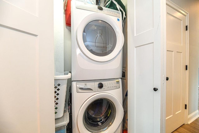 laundry room featuring hardwood / wood-style flooring and stacked washer / dryer