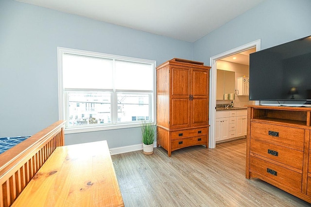 bedroom with connected bathroom and light hardwood / wood-style floors