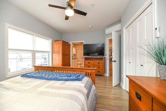 bedroom featuring a closet, light hardwood / wood-style flooring, ceiling fan, and an AC wall unit