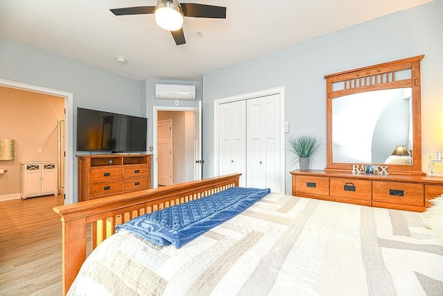 bedroom featuring an AC wall unit, a closet, ceiling fan, and light hardwood / wood-style flooring