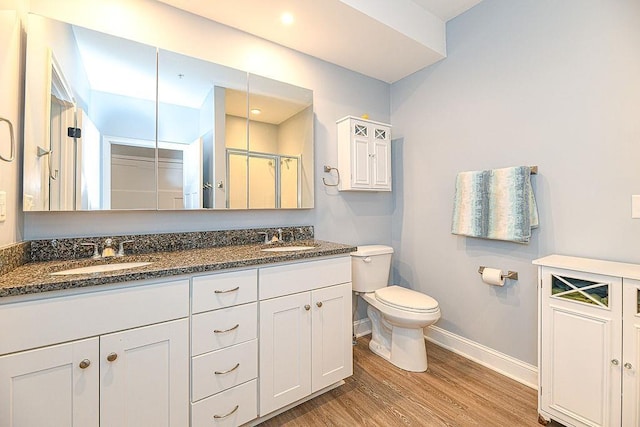 bathroom featuring toilet, vanity, wood-type flooring, and walk in shower