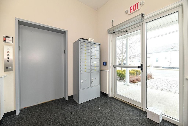 doorway to outside with dark colored carpet, a mail area, and elevator