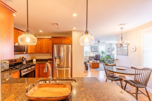 kitchen with ceiling fan with notable chandelier, decorative light fixtures, light wood-type flooring, and stainless steel appliances