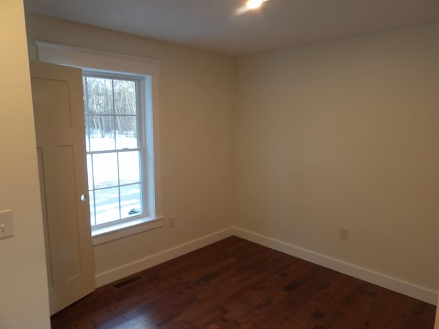 spare room with a healthy amount of sunlight and dark hardwood / wood-style flooring