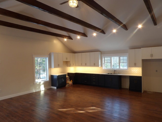 kitchen featuring dark wood-type flooring, sink, tasteful backsplash, high vaulted ceiling, and white cabinets