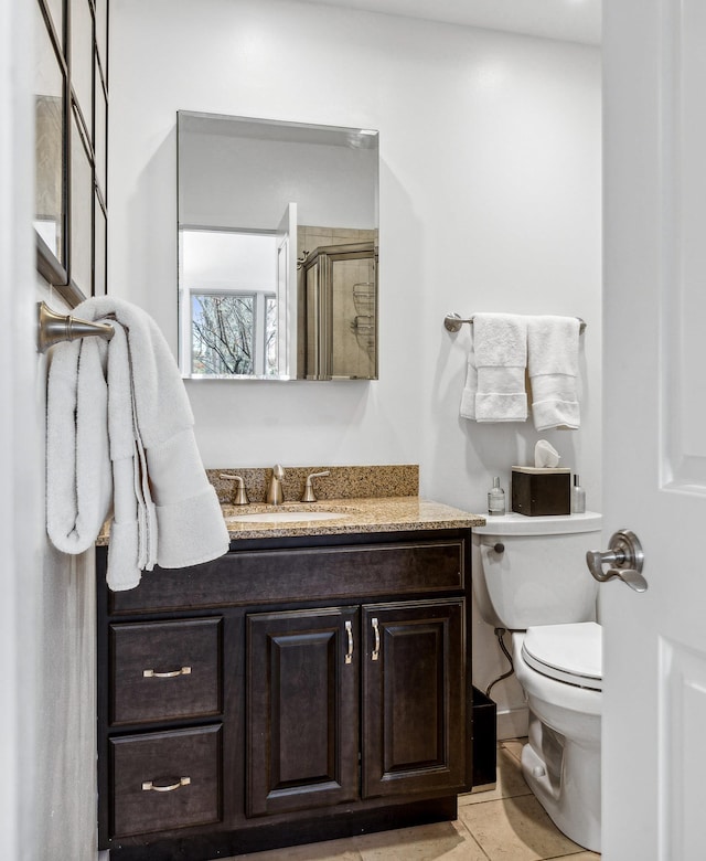 bathroom with tile patterned floors, vanity, toilet, and a shower with shower door