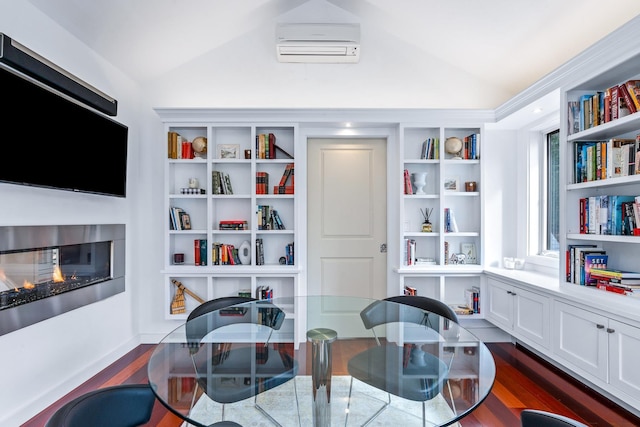 sitting room with dark hardwood / wood-style floors, vaulted ceiling, and a wall unit AC