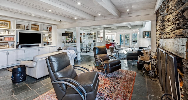 living room with french doors, wood ceiling, built in shelves, beamed ceiling, and a stone fireplace