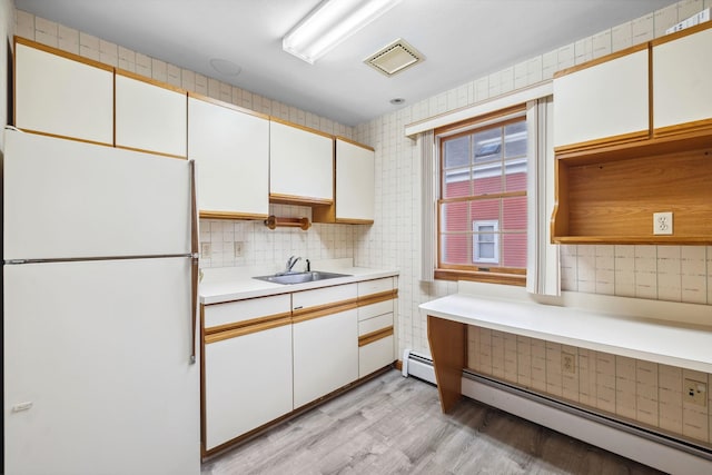 kitchen featuring white refrigerator, light wood-type flooring, white cabinetry, and a baseboard heating unit