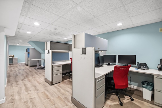 office space with built in desk, light hardwood / wood-style flooring, and a drop ceiling