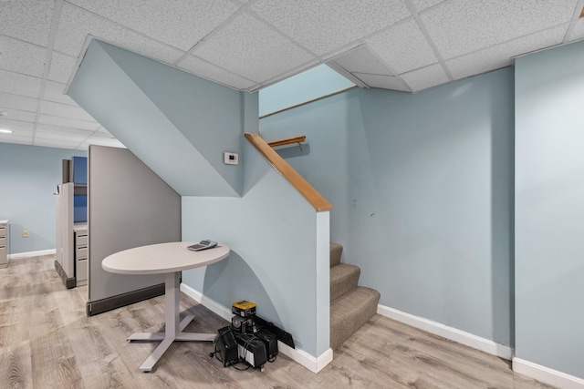 stairway with wood-type flooring and a paneled ceiling