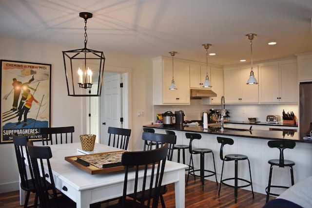 dining space featuring an inviting chandelier, dark wood-type flooring, and sink