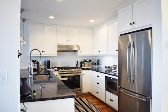 kitchen featuring appliances with stainless steel finishes, dark stone counters, sink, white cabinets, and dark hardwood / wood-style floors