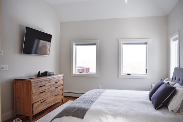 bedroom featuring hardwood / wood-style floors, lofted ceiling, multiple windows, and a baseboard heating unit