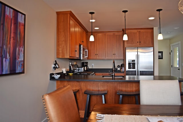 kitchen with kitchen peninsula, stainless steel appliances, hanging light fixtures, and a breakfast bar area