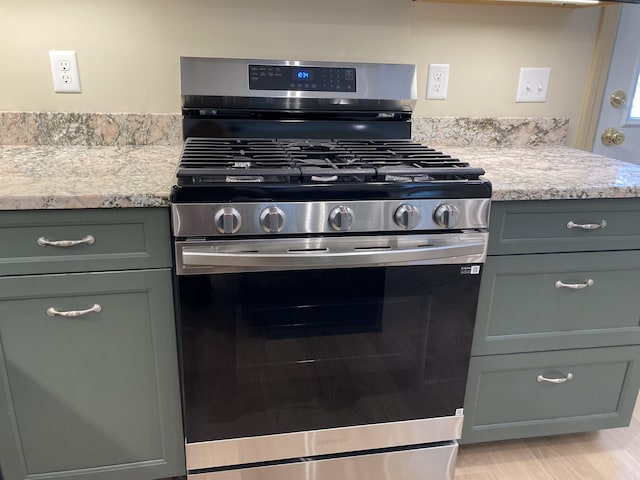 kitchen featuring stainless steel gas stove, light stone counters, and light wood-type flooring