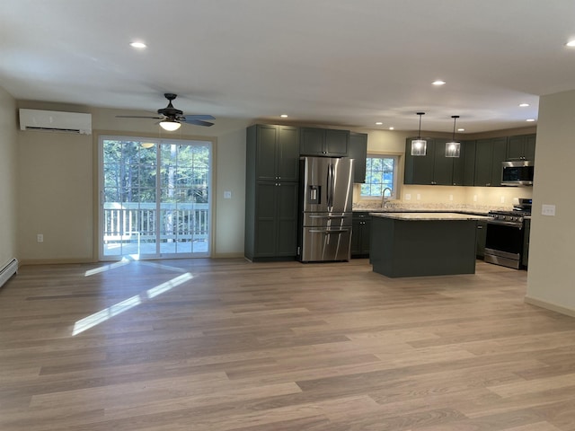 kitchen with light stone countertops, appliances with stainless steel finishes, a wall unit AC, sink, and decorative light fixtures