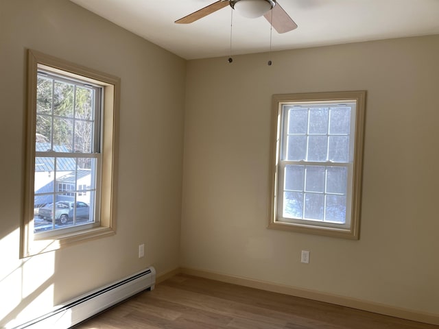 empty room with light wood-type flooring, ceiling fan, and a baseboard heating unit