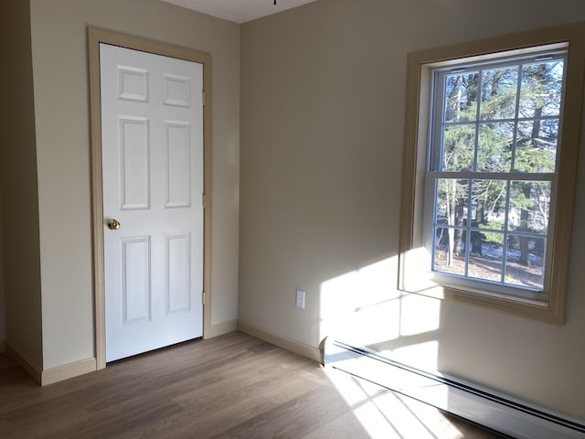 spare room featuring wood-type flooring and a baseboard heating unit