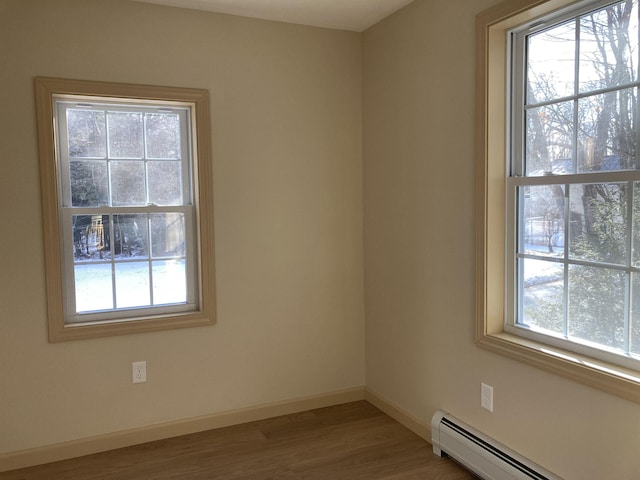 unfurnished room featuring baseboard heating, a wealth of natural light, and light hardwood / wood-style floors