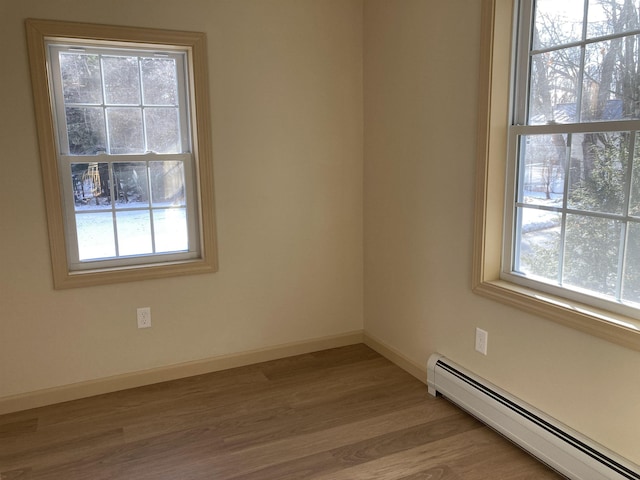 empty room with a wealth of natural light, light hardwood / wood-style flooring, and baseboard heating