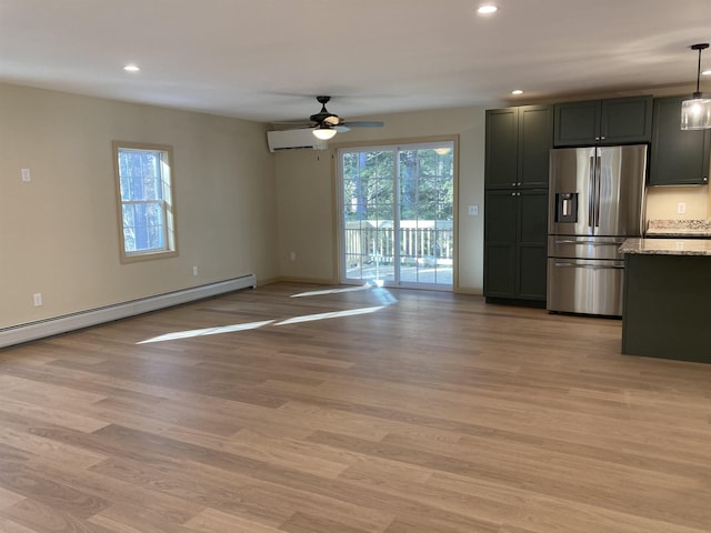 interior space with light stone counters, hanging light fixtures, a healthy amount of sunlight, and stainless steel refrigerator with ice dispenser