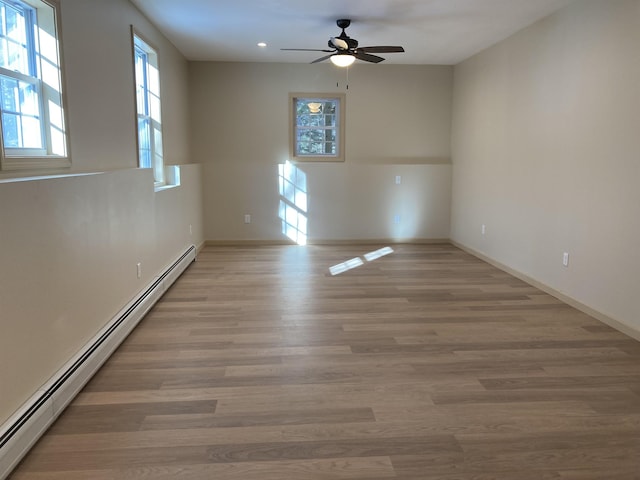 empty room featuring ceiling fan, light hardwood / wood-style flooring, and a baseboard heating unit