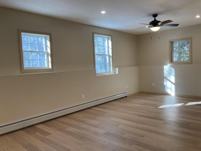 empty room featuring light wood-type flooring, a baseboard radiator, and a wealth of natural light