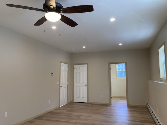 spare room featuring light wood-type flooring, a baseboard radiator, and ceiling fan