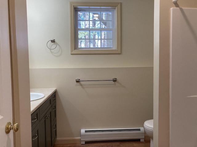 bathroom featuring vanity, hardwood / wood-style flooring, toilet, and baseboard heating