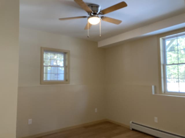 spare room featuring baseboard heating, ceiling fan, and wood-type flooring