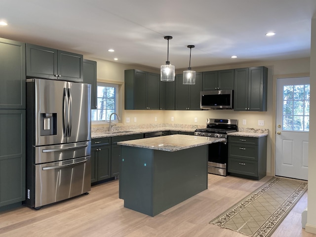 kitchen featuring appliances with stainless steel finishes, light hardwood / wood-style floors, pendant lighting, and sink