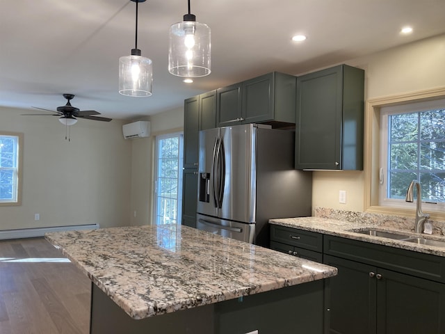 kitchen with a wall mounted air conditioner, stainless steel fridge, sink, a center island, and hanging light fixtures