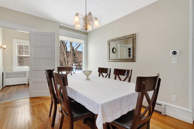 dining area with a notable chandelier, light hardwood / wood-style floors, radiator heating unit, and a baseboard heating unit