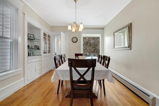 dining space with light wood-type flooring, an inviting chandelier, a baseboard heating unit, and crown molding