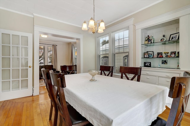 dining room featuring a chandelier, light hardwood / wood-style flooring, and crown molding