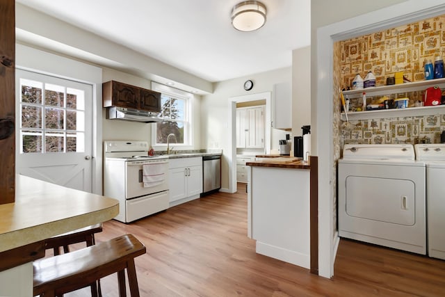 kitchen featuring white electric range, independent washer and dryer, stainless steel dishwasher, and light hardwood / wood-style floors