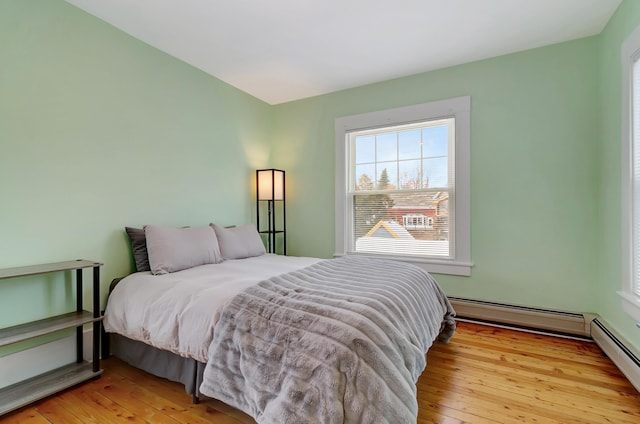 bedroom with baseboard heating and light hardwood / wood-style floors