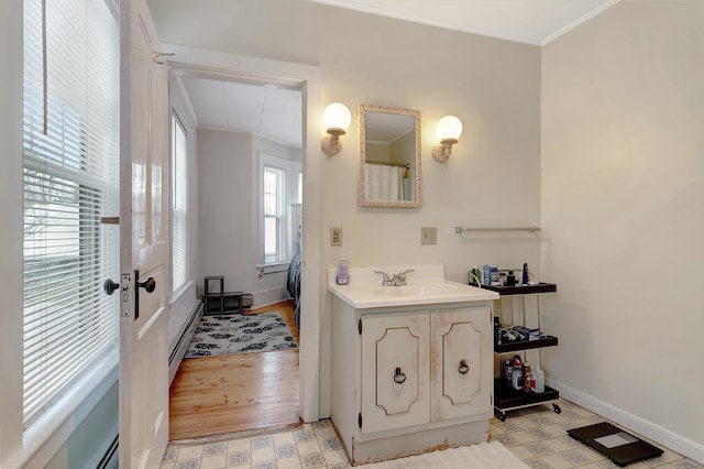 bathroom with vanity, hardwood / wood-style flooring, a baseboard radiator, and crown molding