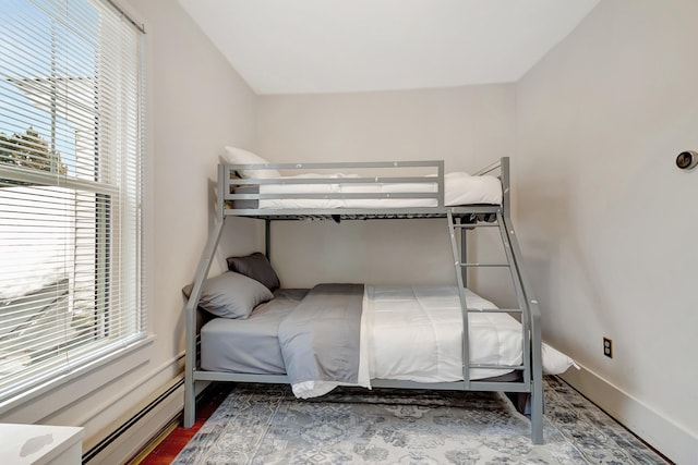 bedroom with wood-type flooring and a baseboard heating unit