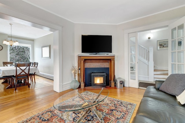 living room featuring a wood stove, ornamental molding, wood-type flooring, and a notable chandelier