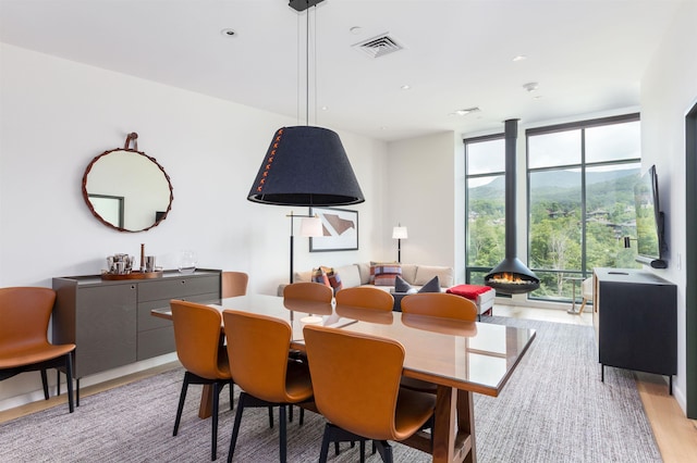 dining space featuring a wood stove, expansive windows, and light wood-type flooring