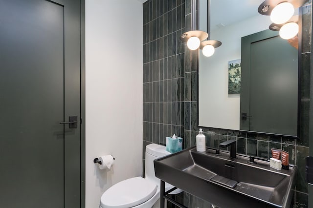 bathroom with decorative backsplash, toilet, and sink