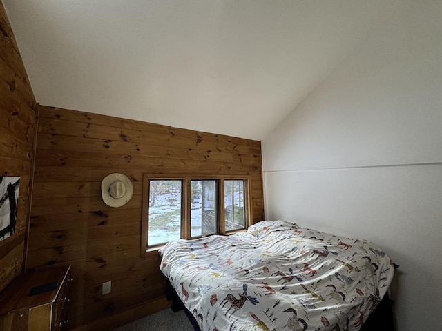 bedroom featuring wooden walls and vaulted ceiling