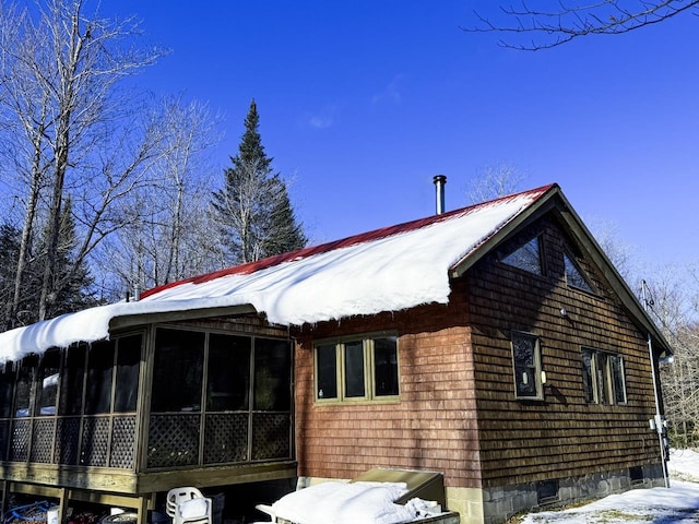 view of snowy exterior with a sunroom