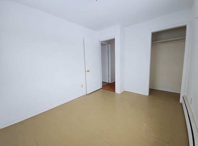 unfurnished bedroom with a closet, light hardwood / wood-style flooring, and a baseboard radiator