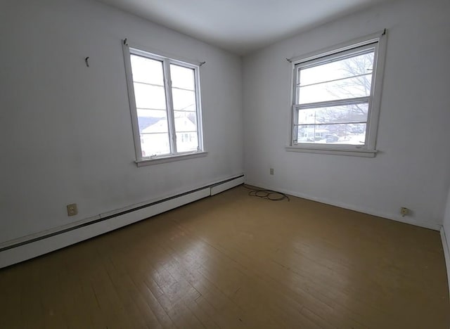 empty room featuring hardwood / wood-style floors and a baseboard heating unit