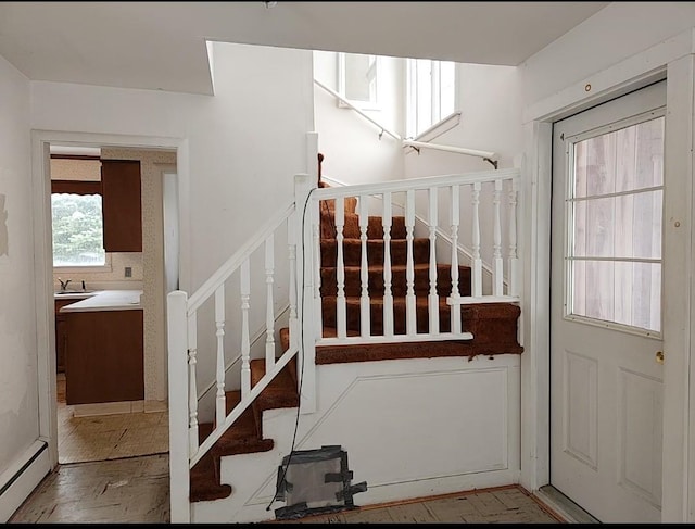 stairway with sink and a baseboard heating unit