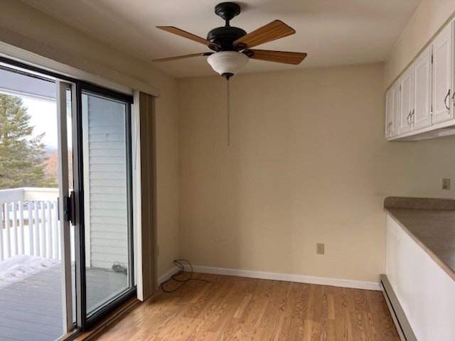 interior space with baseboard heating, ceiling fan, and light wood-type flooring