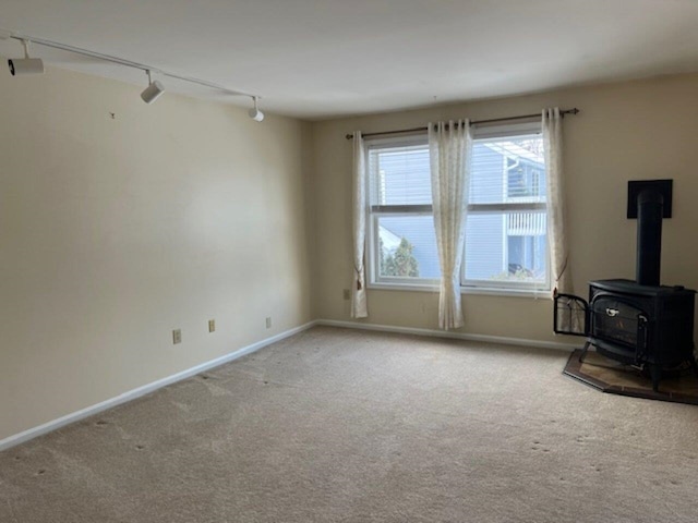 living room with carpet flooring, a wood stove, and rail lighting